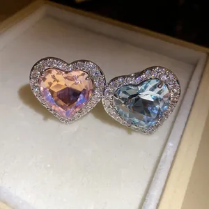 Close-up macro view of heart-shaped pink and blue zircon rings with sparkling halo