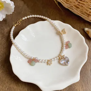 Detailed view of an elegant pearl necklace featuring zircon heart and butterfly charms on a plate