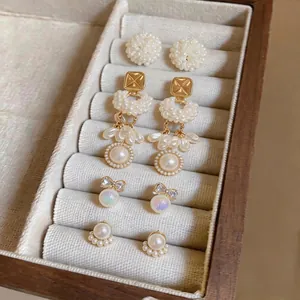 Elegant French style pearl earring set featuring bow and floral motifs in jewelry box.
