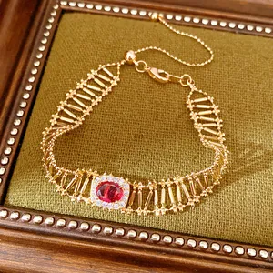 Primer plano de una pulsera calada de oro vintage con una circonita roja ovalada central