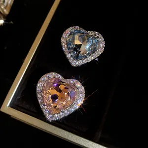 Detailed macro shot of sparkling blue and pink heart-shaped zircon rings in a black box.