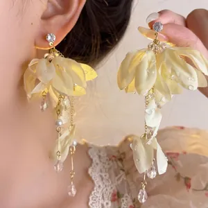 Detail view of elegant yellow fabric flower tassel earrings with pearls and crystal drops.