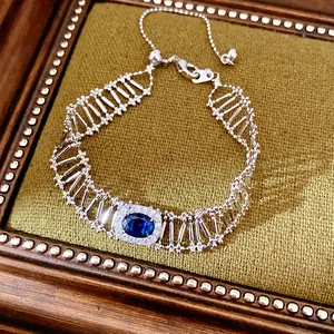 Primer plano de una elegante pulsera plateada calada con circonita azul ovalada central