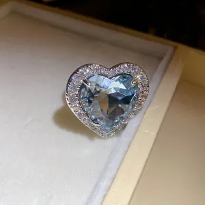 Close-up detail of an elegant heart-shaped blue zircon ring with sparkling diamond border