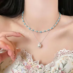 Primo piano di una collana a due strati con perle turchesi e ciondolo di perla.