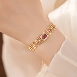 Primer plano de una pulsera calada de oro vintage con una piedra de circón rojo óvalo