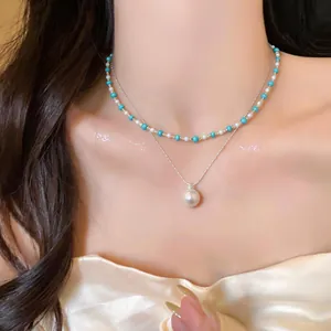 Dettaglio di un'elegante collana a doppio strato con perline e un ciondolo di perla