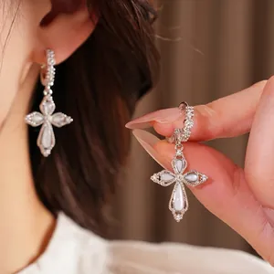 Boucles d'oreilles fleur de croix en zircon portées, bijoux de luxe en finition argentée.