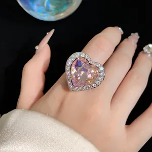 Macro view of an elegant heart-shaped pink zircon ring with diamond halo on a finger
