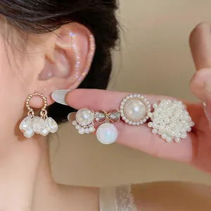 Detailed view of elegant silver needle pearl earrings set with bow and floral cluster designs