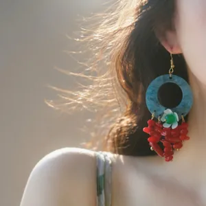 Detailed close-up of Bohemian earrings with blue resin circles and red coral tassels.