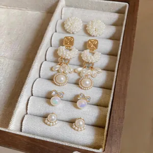 Elegant French style pearl earring set featuring floral and bow designs in luxury jewelry box.