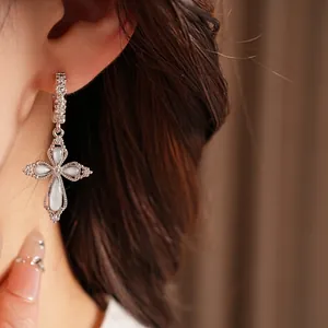 Boucles d'oreilles pendantes croix en zircon avec pierres blanches portées par modèle