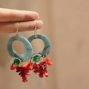 Detailed view of Bohemian resin flower earrings with red coral tassels and blue hoops.