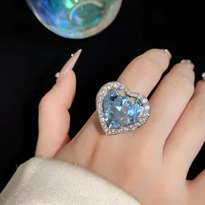 Close-up of a large blue heart zircon ring with pavé rhinestones on finger