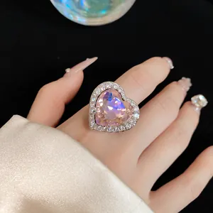 Close-up of a pink heart-shaped zircon ring on a finger with manicured nails