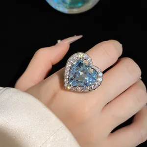 Close-up of luxury heart-shaped light blue zircon ring with sparkling diamond halo.