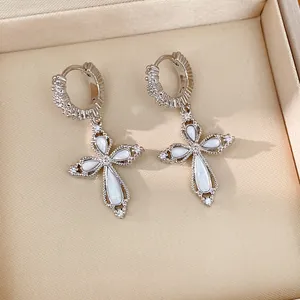 Gros plan d'élégantes boucles d'oreilles croix en argent avec zircone et nacre