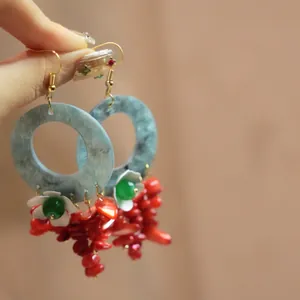 Detailed view of bohemian earrings with blue resin hoops and red coral tassels