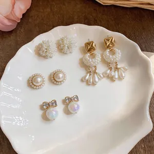 Detailed view of elegant pearl and rhinestone earring set on a white shell tray