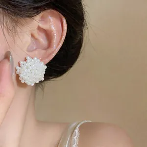 Close-up view of elegant white cluster pearl flower stud earrings worn on female ear