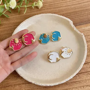 Asymmetric enamel heart stud earrings with sun and moon motifs in gold-tone finish