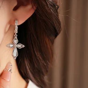 Vue détaillée de boucles d'oreilles croix en argent avec pavé de zircons et pétales