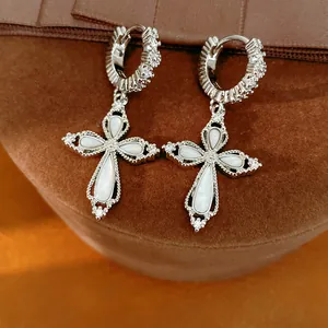 Gros plan d'élégantes boucles d'oreilles croix argentées avec zircone étincelante