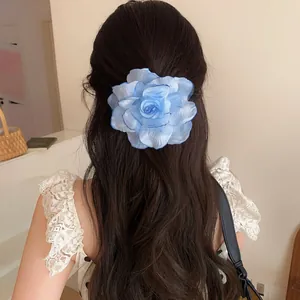 Detailed rear view of a blue gradient fabric rose hair clip on long wavy brown hair