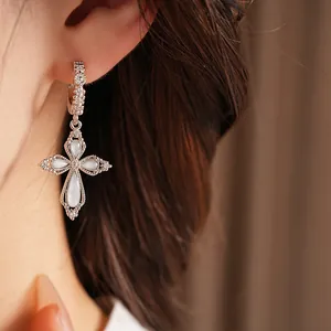 Détail en gros plan d'une boucle d'oreille croix en zircone sur une oreille élégante
