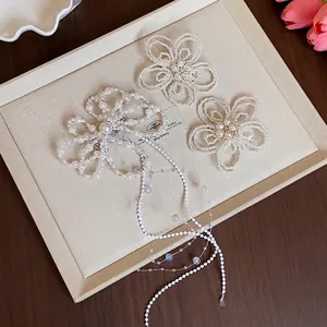 Eleganti fermagli per capelli a fiore di perle con lunghe nappe su un vassoio beige