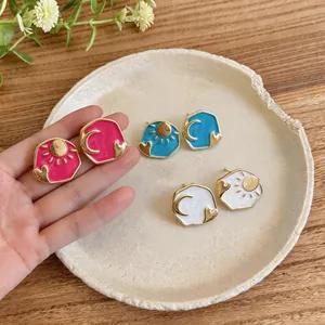 Macro view of colorful enamel sun and moon earrings with gold-tone heart accents.