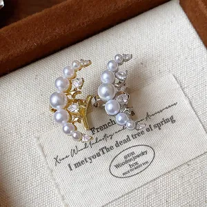 Gros plan sur des boucles d'oreilles lune avec perles et zircons dans leur boîte