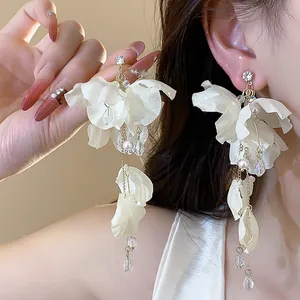 Close-up of white fabric flower earrings with elegant pearl and crystal tassels