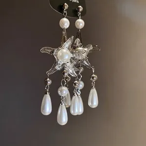 Eleganti orecchini a nappa a stella marina argentati con ciondoli di perle lucide.