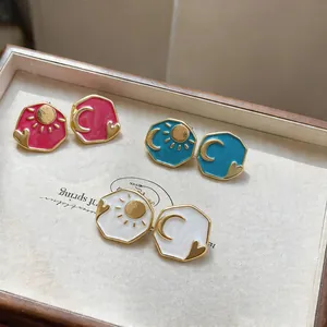 Detail view of asymmetrical enamel stud earrings with sun, moon, and heart motifs in 3 colors