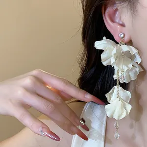 Elegant fabric flower tassel earrings with pearls and crystals on a model's ear.