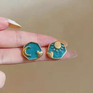 Detailed macro view of blue enamel asymmetrical sun and moon heart stud earrings