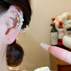Gros plan de la manchette d'oreille lune plaquée or 18k avec perles sur l'oreille