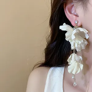 Close-up of elegant cream fabric flower earrings with long pearl tassels