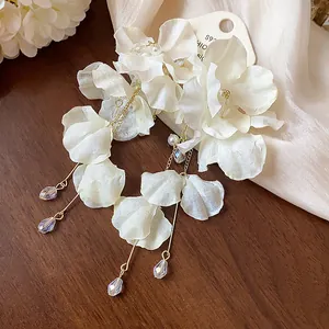 Detailed view of elegant white fabric flower earrings with pearl and crystal tassels.