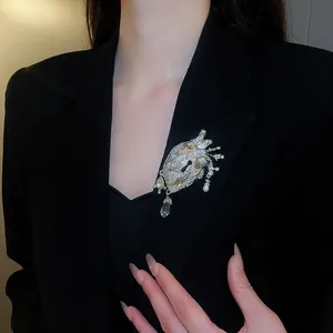Detailed view of an ornate crystal-encrusted anatomical heart brooch on a black blazer