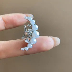 Gros plan d'une bague d'oreille lune avec perles blanches et zircons étincelants