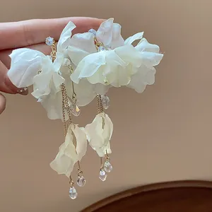 Close-up of white fabric flower earrings with elegant pearl and crystal tassels