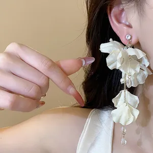 Close-up view of elegant white fabric flower earrings with pearl and crystal tassels