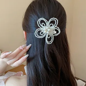 Primo piano di una delicata clip per capelli a fiore di perle su capelli scuri.