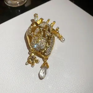 Detailed macro view of a vintage anatomical heart brooch with crystals and dangling pearls