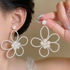 Dettaglio di eleganti orecchini a perno con fiori di perline e perle bianche