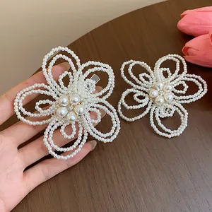 Dettaglio di eleganti fermagli per capelli con fiori di perle bianche su legno scuro