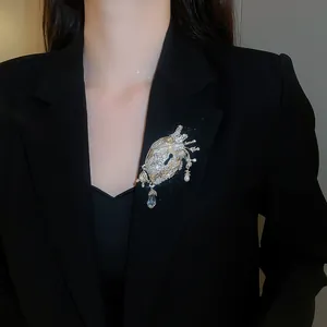 Detailed view of a vintage anatomical heart brooch with crystals on a black blazer.